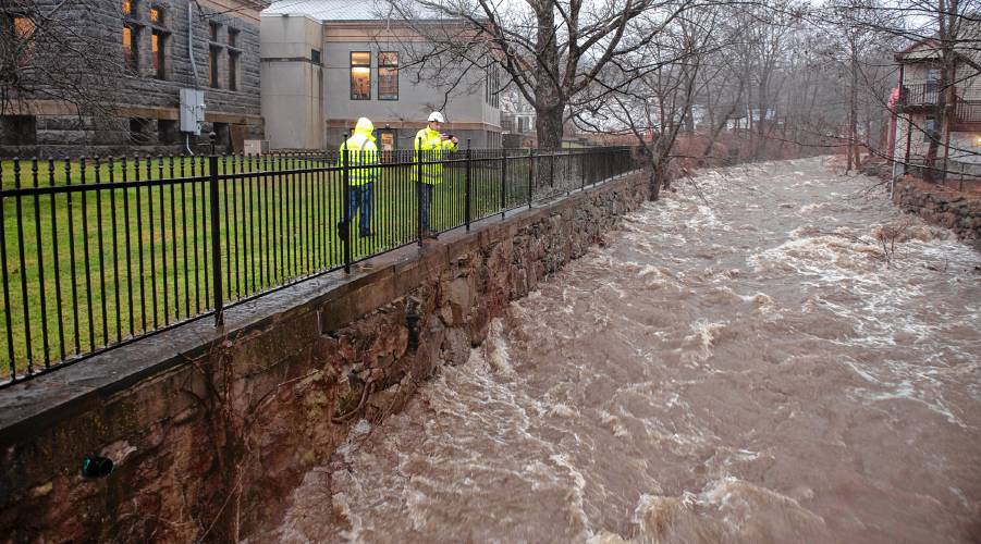 Officials from the Massachusetts Department of Transportation  check the bridge in Williamsburg as the Mill River flows underneath during Monday’s heavy rainfall. 