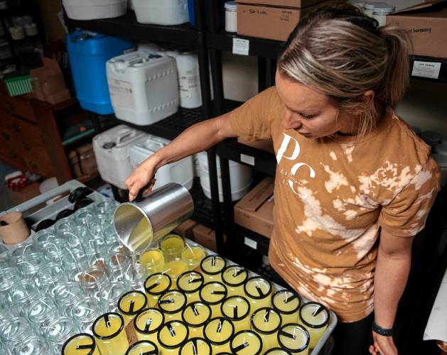Kelsey Wilson, owner of Pearl and Company Natural Candles, pours scented wax into molds at her home office in Chicopee. 