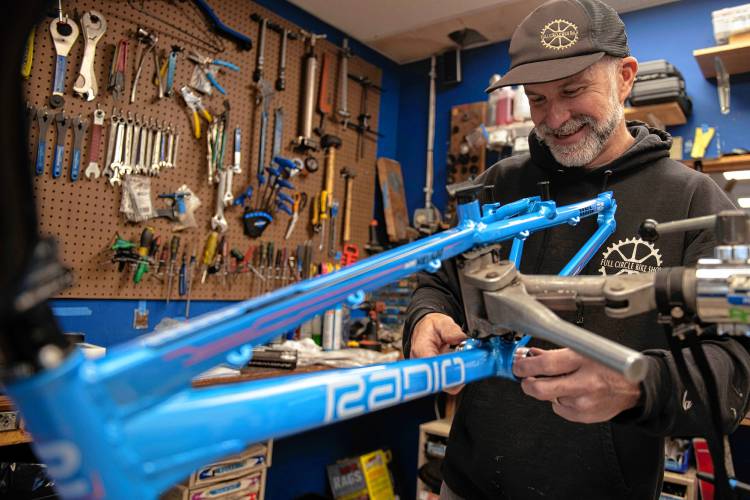 Jason Graves puts together a bike a customer is giving to their child for the holidays at his store in Florence , Full Circle Bike Shop .