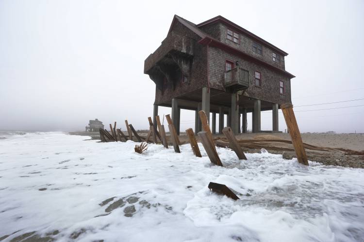 Houses resting on pylons are elevated above waves on the beach, Thursday, Jan. 25, 2024, in South Kingstown, R.I. Experts say erosion and receding shorelines are becoming more common due to ocean rise and climate change.
