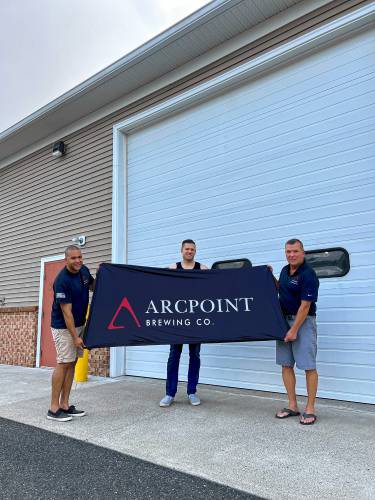 Arcpoint Brewery partners, from left, CJ Eldridge, Chris Peterson, and Dave Pare pose in front of the new brewery space in Belchertown shortly after signing the lease for 30 Front St.