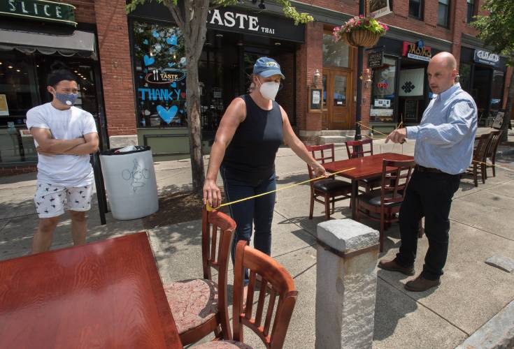 Robert Mora, right, who is the building commissioner for Amherst, directs the placement of tables as Gabrielle Gould, the executive director of Amherst BID, holds a measuring tape as they prepare for outdoor dining, Friday, June 26, 2020 on North Pleasant Street. Tenzin Soepa, of MoMo Tibetan Restaurant, looks on. 
