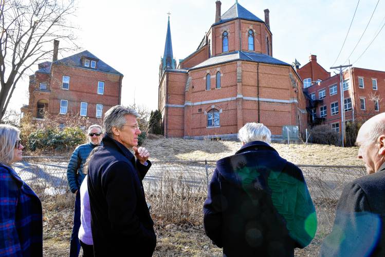 U.S. District Court Judge Mark Mastroianni  (left in dark coat), views the rear of St. Mary of the Assumption Church in Northampton.  The Roman Catholic Diocese of Springfield has filed a lawsuit against Northampton because of a stop-work order to halt the removal of stained glass windows from the property. The church is trying to sell the property.