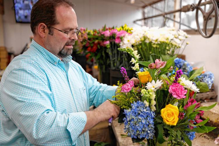 Seth Carey, fourth-generation owner of Carey’s Flowers, works on an arrangement Thursday afternoon at the store in South Hadley.