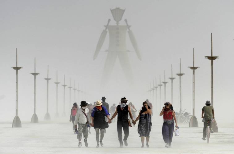 Burning Man participants walk through dust at the annual Burning Man event on the Black Rock Desert of Gerlach, Nev., on Friday, Aug. 29, 2014. Burning Man organizers don’t foresee major changes in 2024 thanks to a hard-won passing grade for cleaning up this year’s festival.