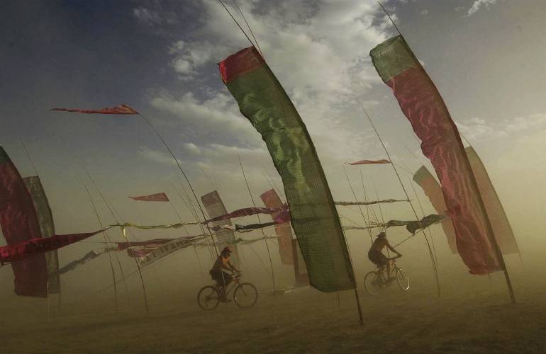 Bicyclists make their way through an art installation at the Burning Man counter-culture arts festival, Wednesday, Sept. 1, 2004, in Gerlach, Nev. Burning Man organizers don’t foresee major changes in 2024 thanks to a hard-won passing grade for cleaning up this year’s festival.
