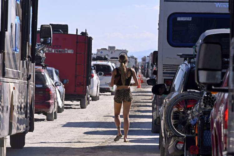 A woman walks between cars exiting the Burning Man festival, Sept. 5, 2023, in Black Rock Desert, Nev. Burning Man organizers don’t foresee major changes in 2024 thanks to a hard-won passing grade for cleaning up this year’s festival. Some feared their pledge to “leave no trace” might be too tall of a task after a rainstorm turned Nevada’s high desert into a muddy quagmire, temporarily delaying the departure of some 80,000 revelers over the Labor Day holiday.