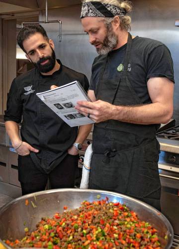 Mohamed Alqamoussi, a culinary specialist with the National Humane Society, looks over a recipe with Caleb Murray, a chef with residential dining at Smith College, during a training in plant-based foods. The training focused on breakfast and brunch.