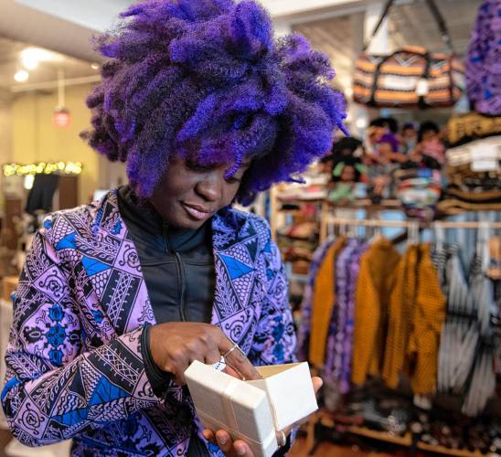 Aimee Salmon, owner of Positively Africana in Thornes Marketplace in Northampton, looks through new merchandise before placing it in her shop before opening Tuesday morning.
