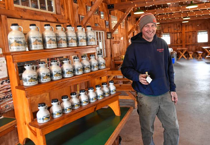 Chip Williams of the Williams Farm Sugar House in Deerfield next to some maple syrup for sale.