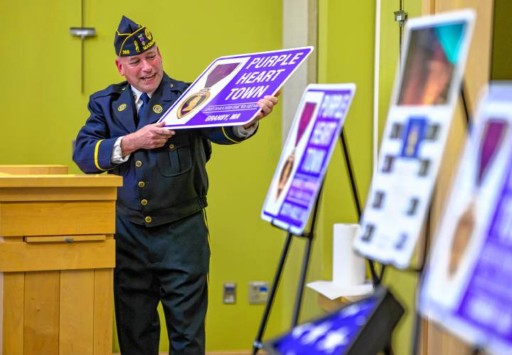 Brian Willette, commander of South Hadley American Legion Post 260,  displays a Purple Heart sign in honor of Granby resident Lenny Desrochers during South Hadley’s National Vietnam War Veterans Day Commemoration at the South Hadley Public Library on Thursday.