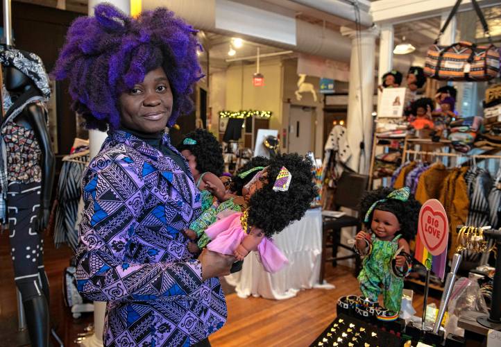 Aimee Salmon, owner of Positively Africana in Thornes Marketplace in Northampton, holds some of the many dolls she sells in her shop.