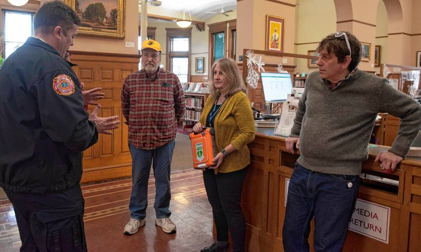 Forbes Library Director Lisa Downing and Lilly Library Director Adam Novitt, right,  talk with Matt Lemberg, assistant fire chief for the Northampton Fire Department,  left, and Phil Giers, a Northampton Lions Club member, about the new automated external defibrillator machines the club donated to both libraries on Wednesday. 