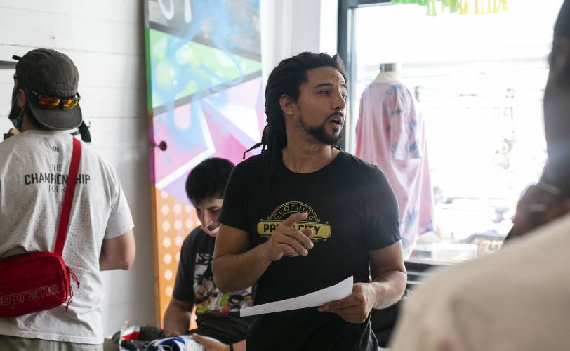 Paper City Clothing Co. co-owner Carlos Peña talks with customers in August 2021 in Holyoke