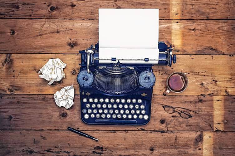 Top view thirties retro writers desk with typewriter on old wooden background table top.