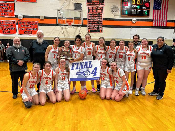 The South Hadley girls basketball team poses with the Final Four trophy and banner after advancing with a thrilling 53-46 overtime win over Cohasset in the MIAA Division 4 Elite Eight on Thursday night at South Hadley High School.