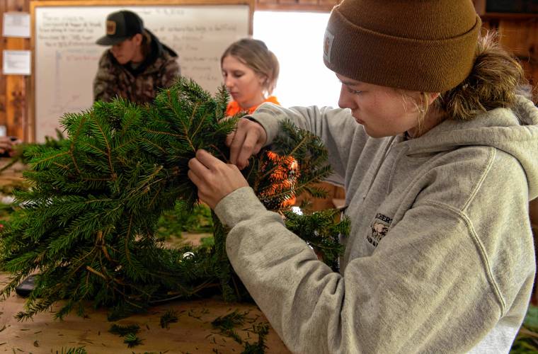 Smith Vocational and Agricultural High School student Violet Geoffrion makes wreaths with other students in half of the horticultural building not lost to fire last year. The school is looking to raise the remaining $750,000 of a $6.7 million project to construct a new building. In the background are students  Sam Jenkins and Shelby Frey.