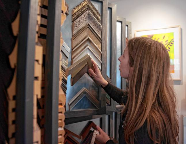 Katie Bete, an employee of  Hope and Feathers, owned by Michelle Raboin, gets frames ready for display  in new space at 238 Bridge St. in Northampton. 