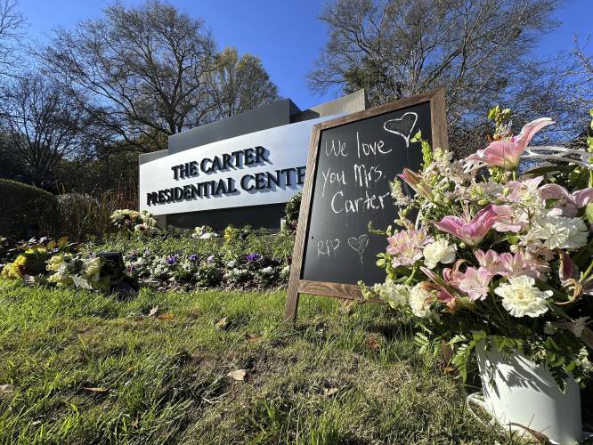 Bouquets of flowers and a sign in tribute to Rosalynn Carter are seen at The Carter Presidential Center in Atlanta, on Monday. The former U.S. first lady died on Nov. 19. She was 96.