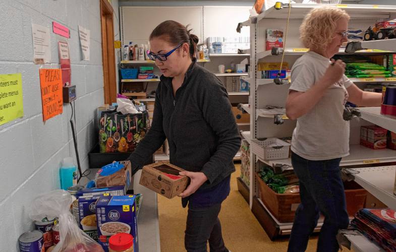 Anya Loughran and Sarah Smith, volunteers with Neighbors Helping Neighbors food pantry in South Hadley, gather items to fill orders to be delivered to those who are homebound. 