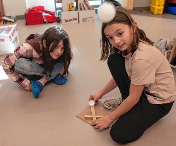  Reilly Keefe, left, and Sadie Lopes, fourth graders, watch to see if the ball will hit the target when launched from the catapult they built in the STEAM class taught by Megan Kelley Bagg at Mountain View School in Easthampton.