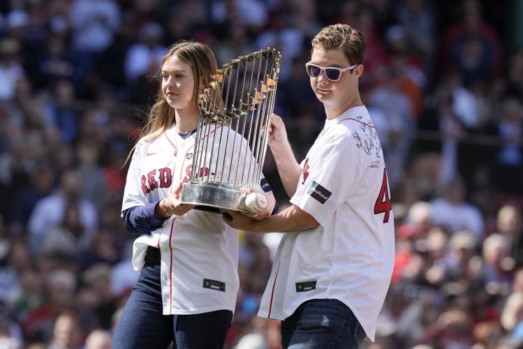 Children of former Boston Red Sox's Tim Wakefield, Brianna, left, and Trevor carry the World Series trophy after Brianna threw out the ceremonial first pitch during pre-game ceremonies before an opening-day baseball game at Fenway Park against the Baltimore Orioles, Tuesday, April 9, 2024, in Boston. (AP Photo/Michael Dwyer)