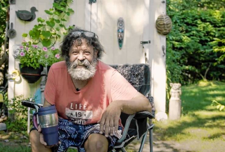 Jim Mias of Leeds, who’s profiled in the short film “Small Lives,” is seen here in his backyard. His T-shirt has a phrase that sums up his general view of things: “Life is good.”