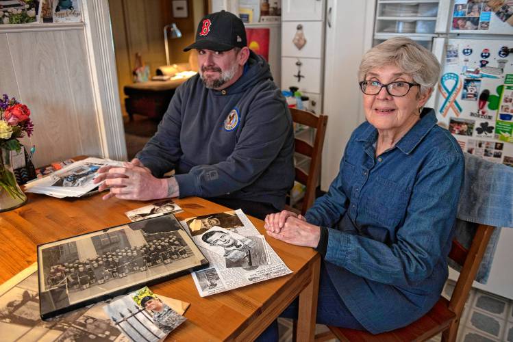 Brendan Quinn and his mother, Cheryl Quinn, sit with photographs of his great-uncle and her uncle, Merle Chester Joseph Hillman. 