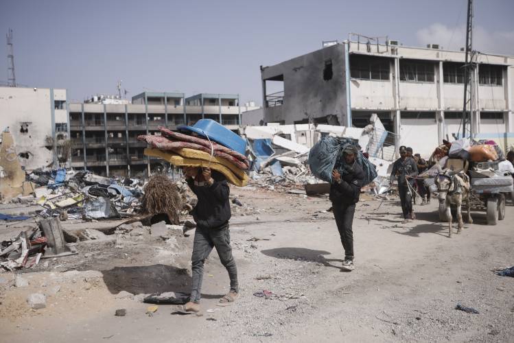 Palestinians carry their belongings on March 6 after visiting their houses destroyed in the Israeli offensive on Khan Younis, Gaza Strip.