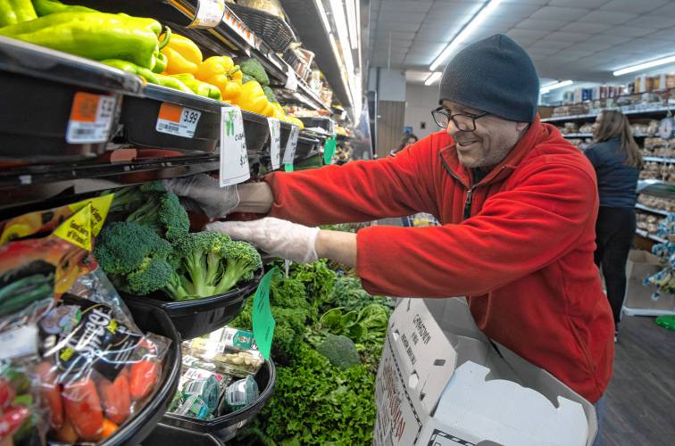 Romi Rohit, an employee at Fruit Fair in Chicopee, stocks vegetables.