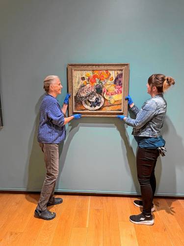 Curators at the D’Amour Museum of Fine Arts in Springfield ready a work for “As They Saw It: Women Artists Then & Now.”