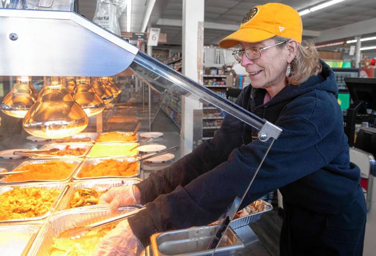 Donna DeGray, who works in the deli at Fruit Fair in Chicopee, refreshes the hot bar in the store.