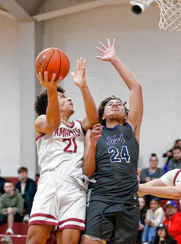 Amherst’s Brandon Stewart (21), left, drives to the hoop over Sci-Tech’s Jeremiah Rivera (24) in the fourth quarter earlier this season in Amherst.