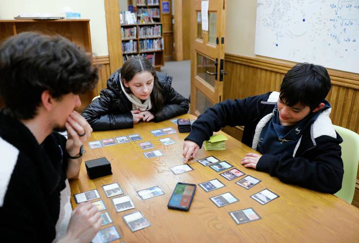 James Echols, left, instructs Betta Cerro, 12, and Angelo Cerro, 11, in a game of Magic: the Gathering on Thursday night at Lilly Library in Florence.