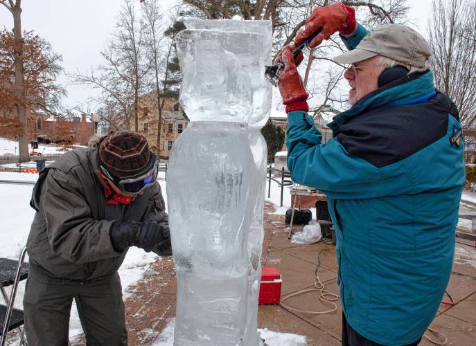 Jeff Zesiger, left, and David Barclay work on an ice sculpture in front of Forbes Library as part of the Northampton Winter festival, which happens on Saturday. 