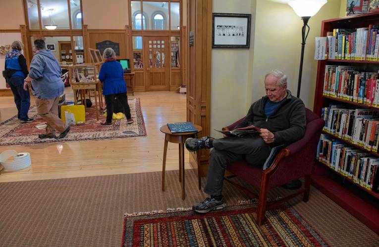Bill Warren kicks back with a magazine while artist hang work for a show in the Hosmer Gallery at Forbes Library.  