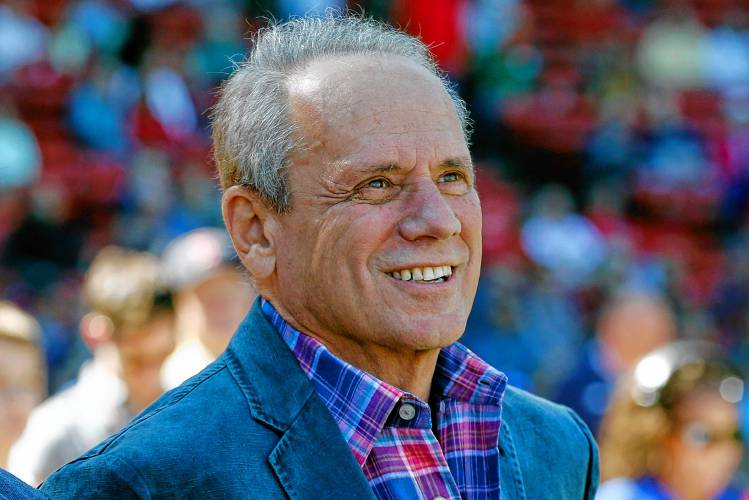 Boston Red Sox president and CEO Larry Lucchino watches a video tribute before a baseball game between the Red Sox and the Baltimore Orioles in Boston, Sunday, Sept. 27, 2015. Larry Lucchino, the force behind baseball’s retro ballpark revolution and the transformation of the Boston Red Sox from cursed losers to World Series champions, has died. He was 78.