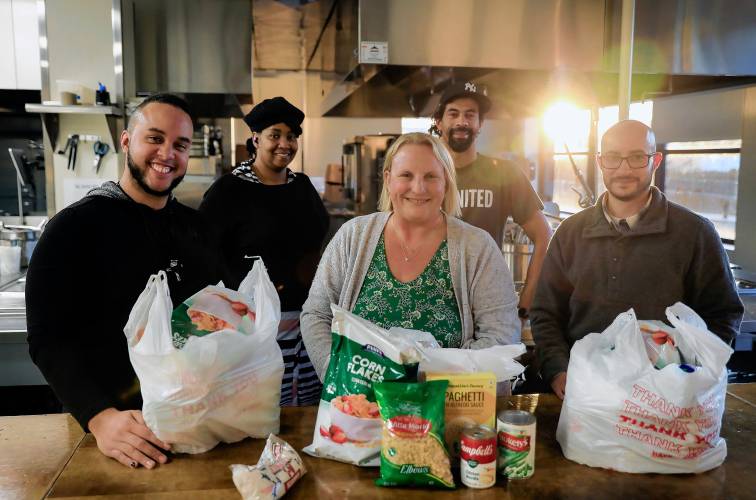 Emmanuel Reyes, from left, Janae Alleyne, Stacy Graves, Miguel Arroyo and Lee Drewitz pose for a photo  with food pantry items for the Holyoke Community Cupboard at the HCC MGM Culinary Arts Institute on Race Street in Holyoke.