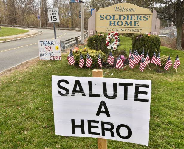 Signs, flags, flowers and wreaths are placed at the entrance to the Soldiers’ Home in Holyoke in April 2020.
