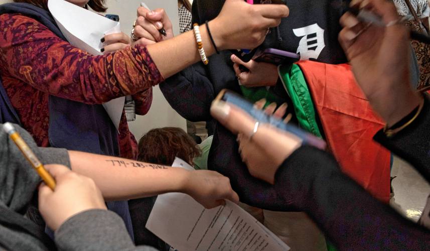 UMass students write their legal representatives' phone numbers on their arms in case of arrest during  a walkout and sit-in event on Wednesday to demand that the university cut ties with weapons manufacturers and condemn Israeli actions in Gaza. 