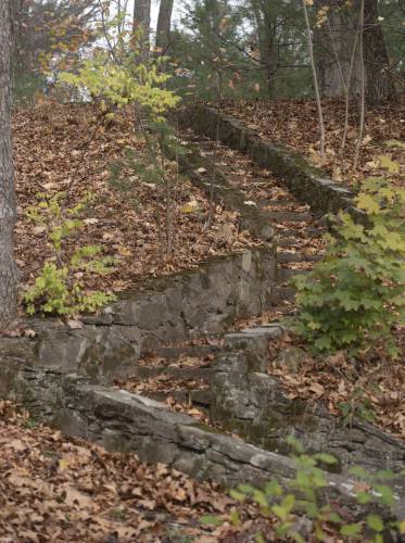 Stone steps that lead to a flat area with scattered metal supports that look as if they used to be for picnic tables at Anniversary Hill Park in Holyoke.
