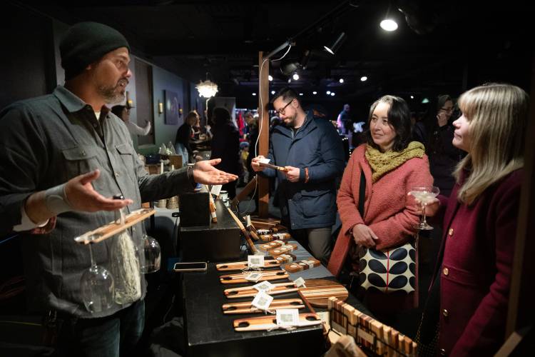 At the 2022 Sip & Shop Stroll event in Amherst, customers chat with Josh Hannon, left, of Hannon Made woodcrafts, at a Makers Market. This year’s stroll is scheduled for Thursday night.