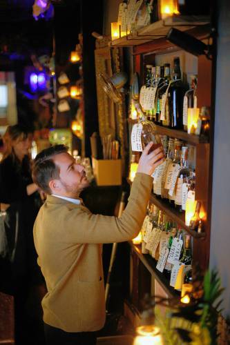 Owner Ned King pulls down a bottle of 1917 Chapin New England rum from his wall of vintage spirits available at Gigantic bar in Easthampton.