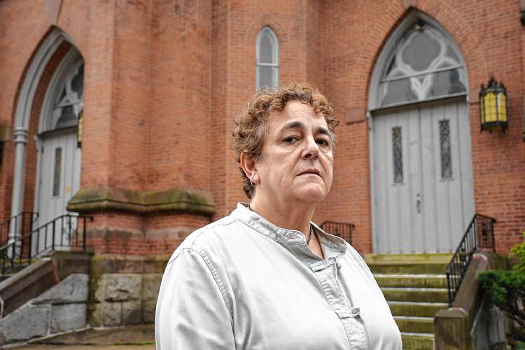 Nancy Dunn stands in front of the former Notre Dame Church on East Main Street in North Adams in October 2021. Dunn was lured into a sexual relationship with a priest while receiving pastoral counseling from him. She is challenging the fact that the diocese has allowed the priest, despite an official sanction after his behavior was reported, to represent the church in local ceremonies.