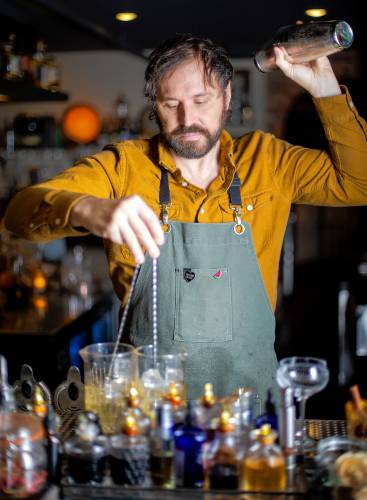 Bartender Nick Martino mixes up a Big in Japan house old fashioned and an El Presidente classic cocktail while shaking a Deeply Rooted original cocktail Tuesday at The Archives bar in Amherst.