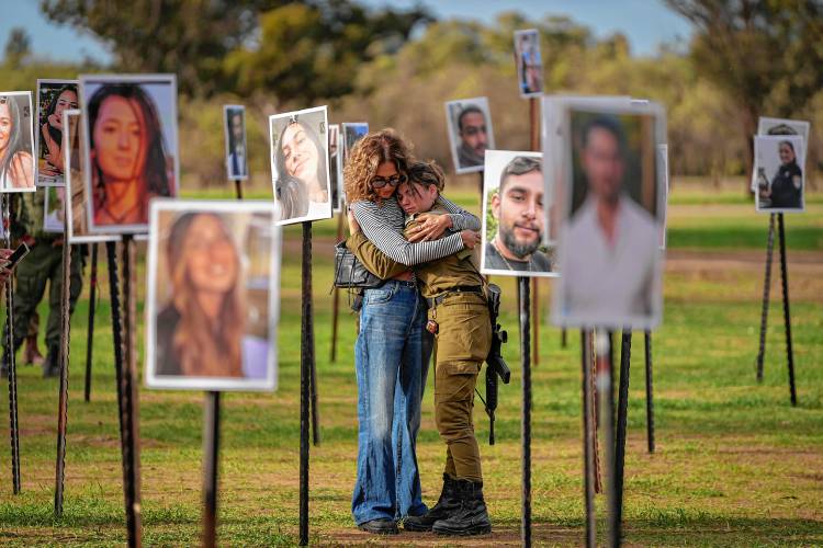 Israelis embrace amid photos of people killed and taken captive by Hamas terrorists during their violent rampage on Oct. 7 through the Nova music festival in southern Israel, which are displayed at the site of the event.
