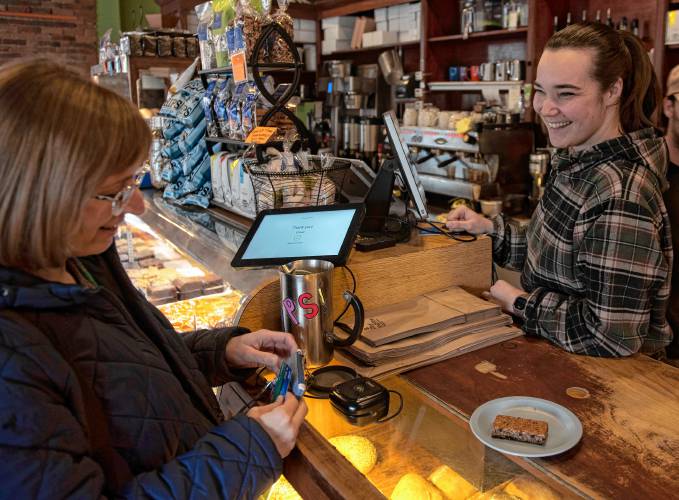 Rebecca Hahn, a manager at Woodstar Café in Northampton, chats with customer Jennifer Fox as she pays for her order on Tuesday. Gov. Maura Healey on Monday filed legislation that would give municipalities the authority to increase local option taxes on meals, lodging and motor vehicles. 