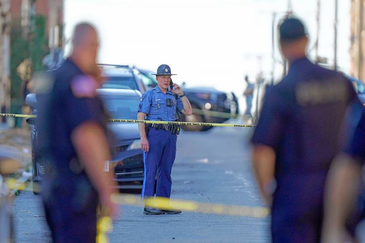 Members of law enforcement stand near police tape while investigating the scene where multiple people were shot, Wednesday, Oct. 4, 2023, in Holyoke.