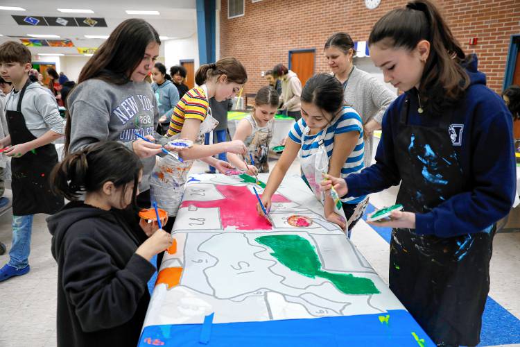 Victoria McKinney, 12, from left, Georgia Dejasu, 12, Leia Nagle, 11, Natalie Dejasu, 8, Jen Godlesky, Allaya Torres-Creek, 12, and Ella Sasser, 13, paint one of 52 mural panels to help create a 1,500-square-foot mural for JFK Middle School during a community painting party Saturday afternoon in the school cafeteria.