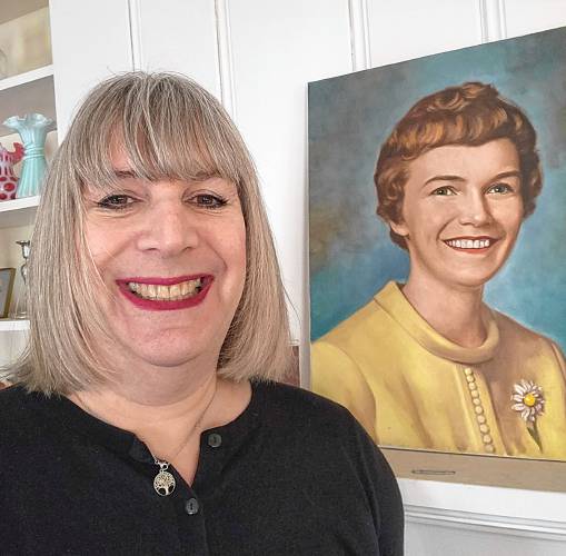 Mariel E. Addis with a painting of her mom in the background.
